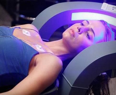 Eliza Dushku in "The Chair" in Dollhouse. Image of Dushku's upper body surrounded my MRI-like hardware
