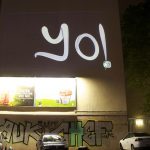 Graffiti lettering "Yo" projected on the side of a large building by Mirae Rosner's group Graffiti Research Lab