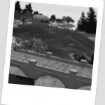 black and white aerial photo of the Lutra region of Second Life showing the fields running from the trestle bridge out to the bay, and including Fiona Blaylock's mobile home parked on a dry, grassy knoll