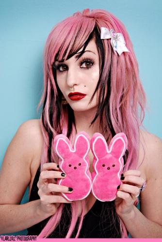 photo of a fair complected girl with pink and black hair and contrasty makup holding two giant pink easter peeps