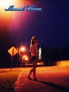 Mermaids and Pissants. "Mermaid Hanna" photo from Hanna Lee's tumblr showing her in an acrid orange-yellow street light at night. The photo is between bolts of thunder and her shorts suggest a hot, balmy night