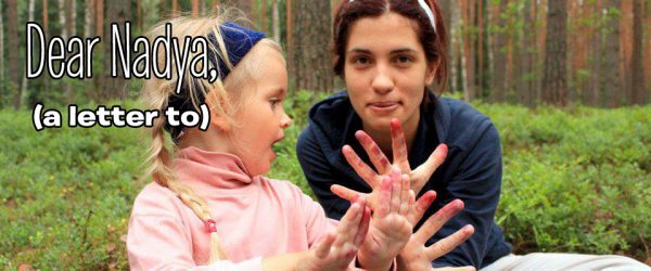 Photo of Nadezhda Tolokonnikova and daughter Gera in the forest with stained hands from something like picking blueberries. Text over the image reads "Dear Nadya (a letter to)
